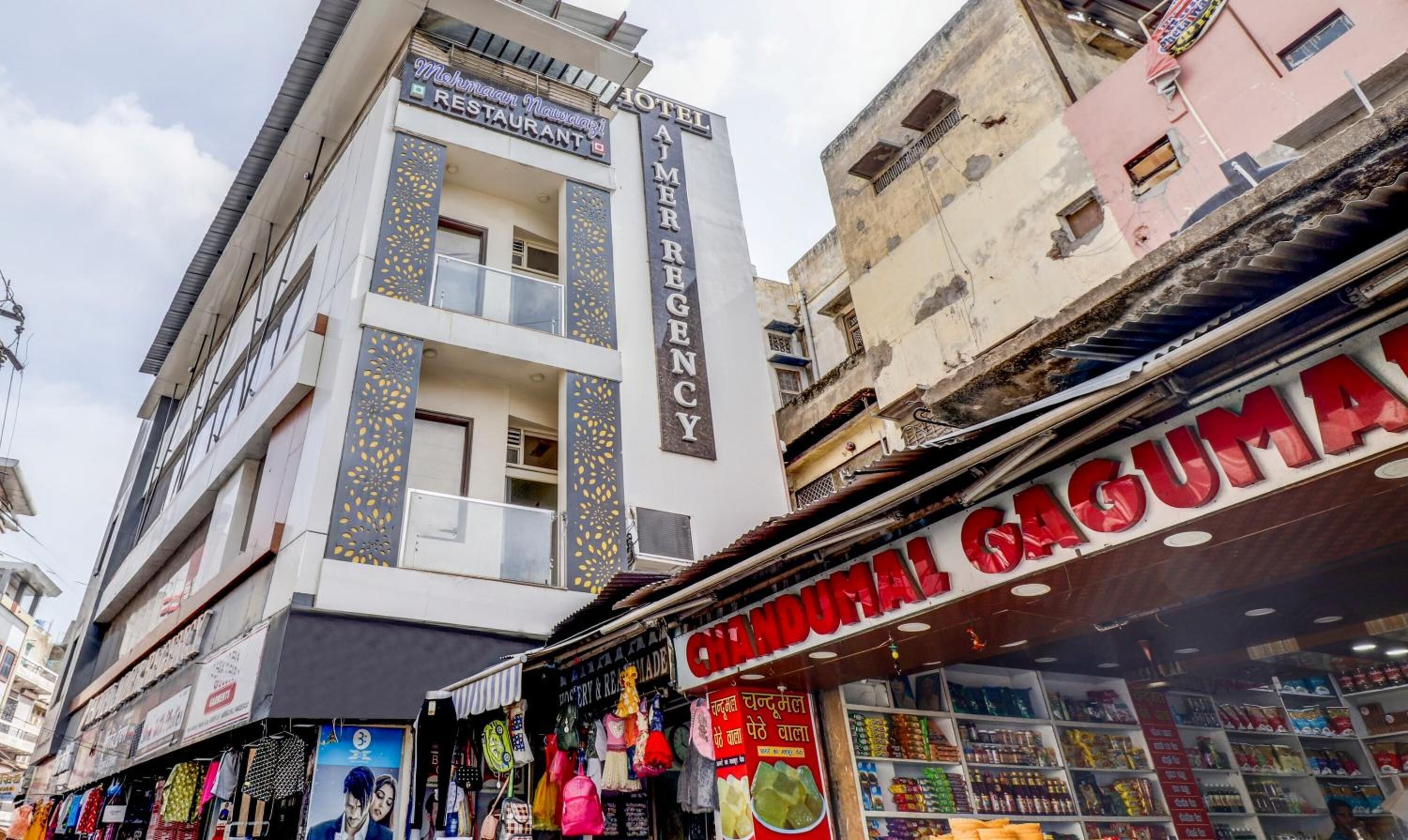 A hotel named "Hotel Ajmer Regency" with a modern facade and a visible emergency exit sign.