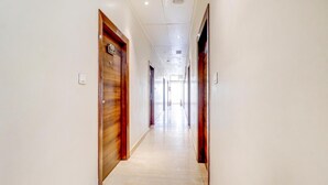 A long, narrow hallway with wooden doors on both sides and a light-colored tiled floor. - Hotel Ajmer Regency (Ajmer)