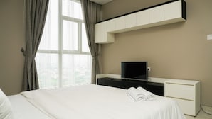 A hotel room with a bed, a TV, a desk, and a window with curtains. - Highest Value 1BR Apartment at Ciputra International (Jakarta)