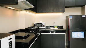 A modern kitchen with dark cabinetry, a microwave, a refrigerator, and a built-in oven. - Highest Value 1BR Apartment at Ciputra International (Jakarta)