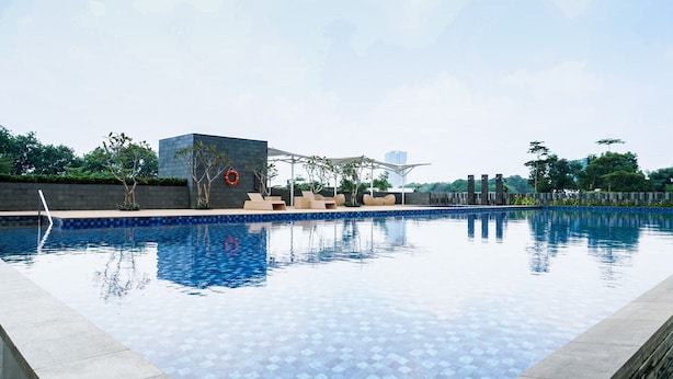 A swimming pool with a tiled edge, lounge chairs, and a pergola structure. - Highest Value 1BR Apartment at Ciputra International (Jakarta)