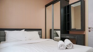 Una camera d'albergo con un letto, un comodino, uno specchio e una porta.