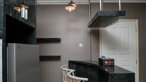 Una cucina moderna con un piano di lavoro in marmo, un frigorifero in acciaio inossidabile, una sedia bianca e una scatola da viaggio sul bancone.