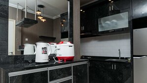Una cucina moderna con pensili in marmo nero, un lavello in acciaio inossidabile e due bollitori sul piano di lavoro.