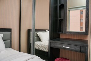 Una habitación de hotel con cama, espejo, mesita de noche y ventana.