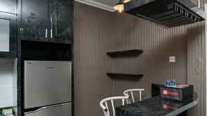 Una cucina moderna con frigorifero in acciaio inossidabile, piani di lavoro in marmo nero e una scatola a marchio travelio sul bancone.