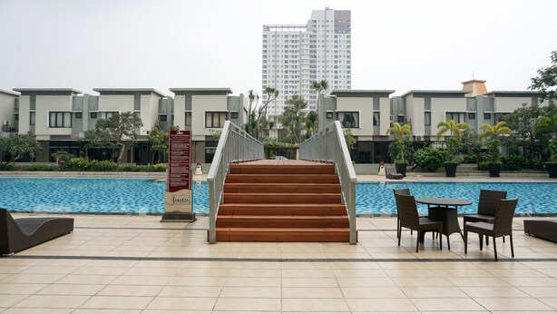 A poolside area with a staircase leading to a building, outdoor seating, and a signboard.