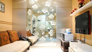 A bedroom with a bed, a desk, a TV, and a decorative partition.