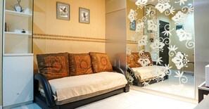 Une chambre à coucher comprenant un lit, un canapé, un miroir et un panneau décoratif mural.