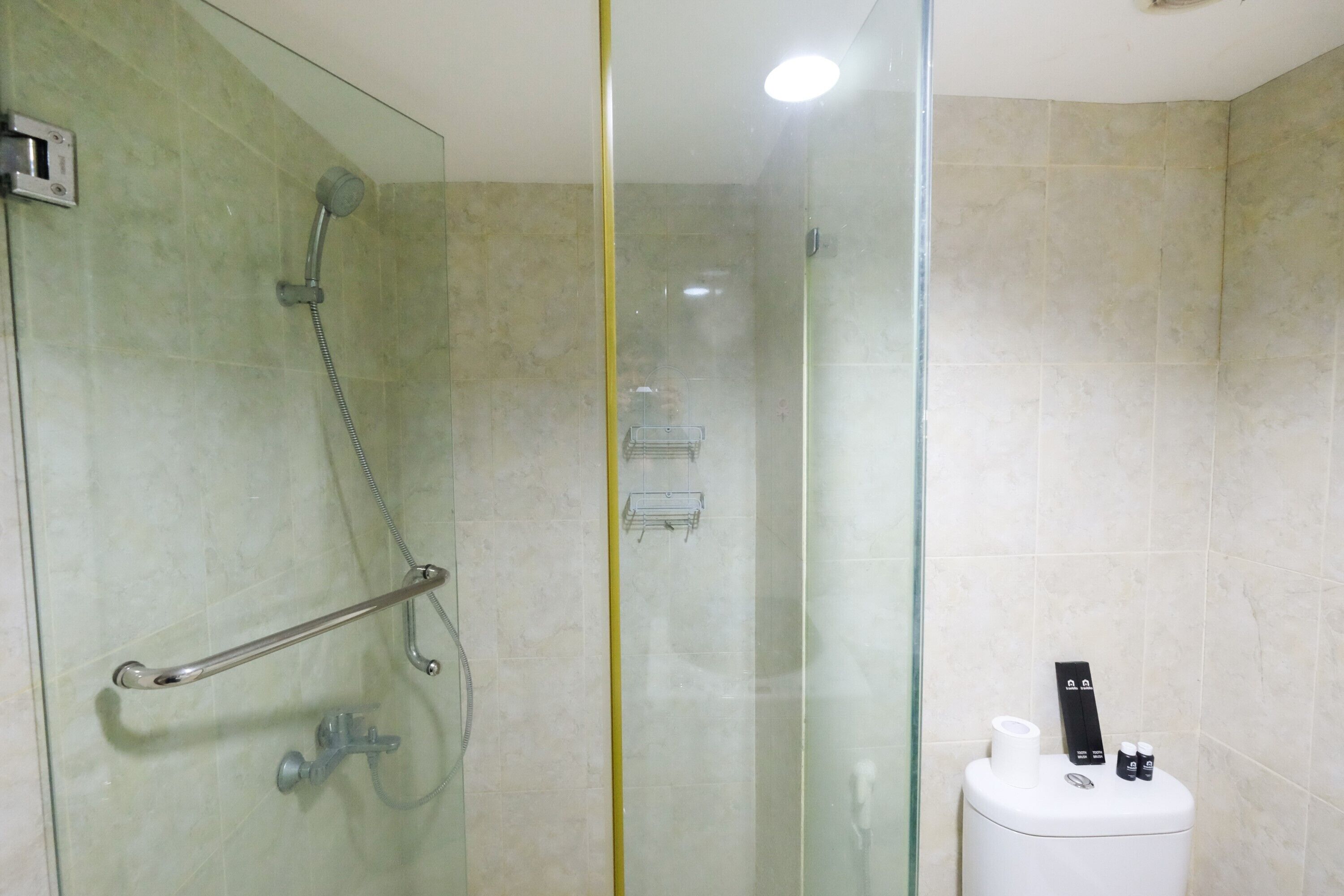 Casa de banho moderna com chuveiro em cabine de vidro, barra de apoio, sanita com função bidé e porta-toalhas.