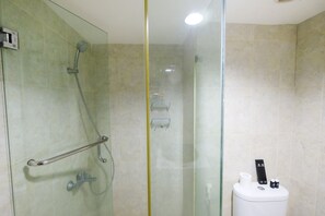 Un baño moderno con ducha acristalada, barra de apoyo, inodoro con función bidé y toallero.