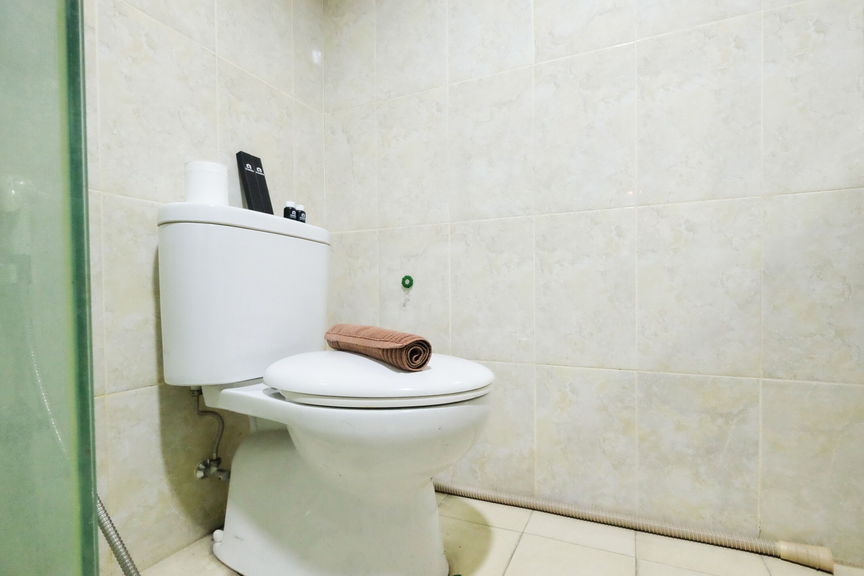 Un bagno con il water, un asciugamano e un pulsante di scarico verde.