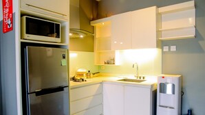 A compact kitchen with a refrigerator, microwave, sink, and water dispenser.