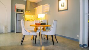 A compact kitchen with a microwave, refrigerator, and a dining area with a table and chairs.
