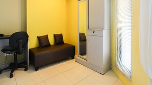 Une petite pièce comprenant un bureau, un canapé et une armoire.