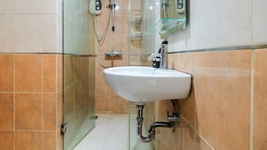 Une salle de bain avec un lavabo blanc, une douche en verre et un miroir au-dessus du lavabo.