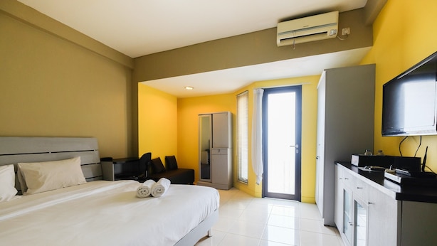 Une chambre d’hôtel équipée d’un lit, d’un bureau, d’une télévision et d’une armoire.