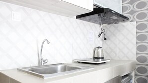 A modern kitchen with a stainless steel sink, a kettle, and a built-in range hood. - Modern 2BR Apartment at Mekarwangi Square Cibaduyut (Bandung)