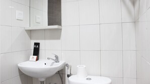 A bathroom with a white sink, a mirror, and a toilet. - Modern 2BR Apartment at Mekarwangi Square Cibaduyut (Bandung)