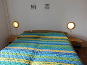 A bed with a colorful quilt, two bedside tables with lamps, and two framed pictures on the wall. - Nice and Cozy Apartment Ferry in Medulin (Medulin)