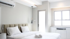 Ett modernt hotellrum med en stor säng, ett sängbord, en inbyggd TV och ett fönster med gardiner.