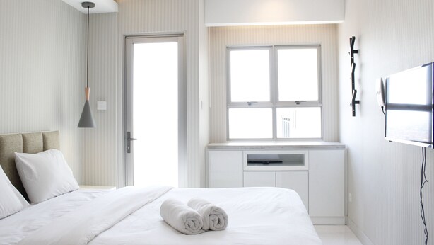 Ett modernt hotellrum med en snyggt bäddad säng, ett stort fönster och en platt-TV som är monterad på väggen.