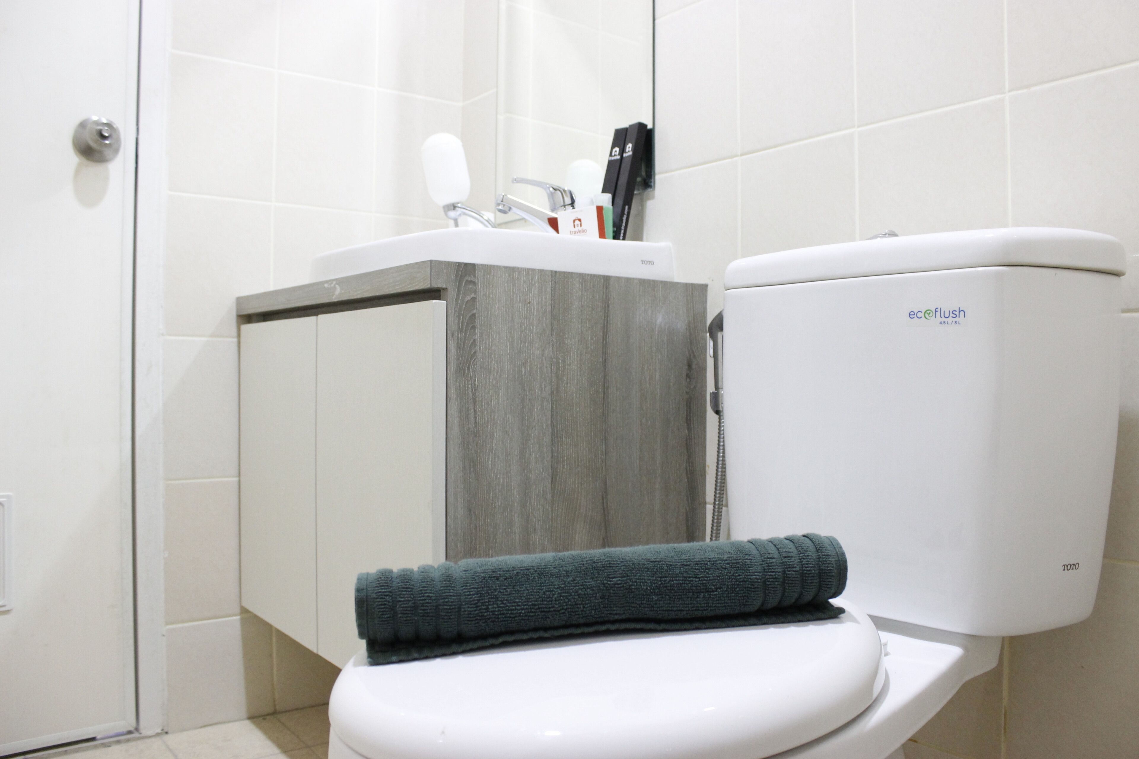 A bathroom with a white toilet, a grey vanity, and a towel on the seat.