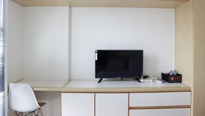 Une chambre d’hôtel équipée d’un bureau, d’une télévision, d’une chaise et d’un mini-bar.