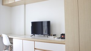 Un bureau minimaliste équipé d’un téléviseur à écran plat, d’un bureau et d’une chaise blanche.