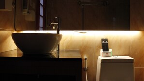 Une salle de bain avec un grand lavabo blanc, un porte-serviettes et des toilettes dotées d’un support pour carte de transport.
