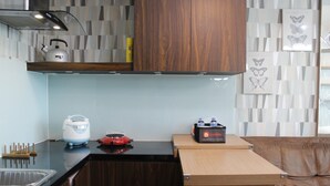 Une cuisine compacte dotée de meubles en bois, d’une bouilloire, d’un grille-pain et d’un distributeur d’eau.