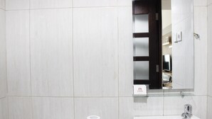 Une salle de bain avec un lavabo blanc, des toilettes et un miroir au-dessus du lavabo.