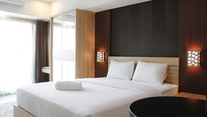 Une chambre d’hôtel moderne avec un grand lit, une table ronde noire et deux appliques murales.
