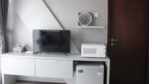A room with a TV, microwave, and refrigerator on a white cabinet. - Stylish 2BR Gateway Pasteur Apartment (Cimahi)