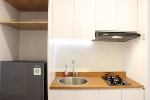 Una cucina compatta con lavello in acciaio inox, piano cottura a gas e forno integrato.
