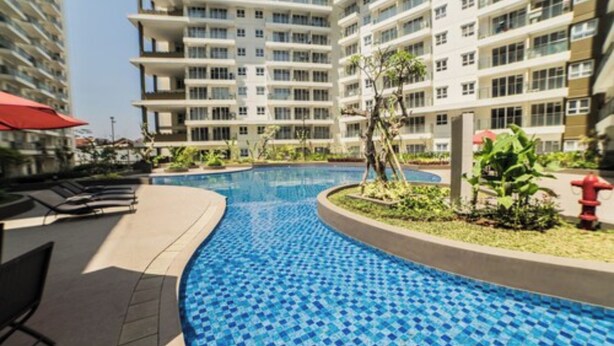 A swimming pool with blue mosaic tiles, surrounded by a low wall and greenery. - Classic and Comfy 2BR @ Gateway Pasteur Apartment (Cimahi)