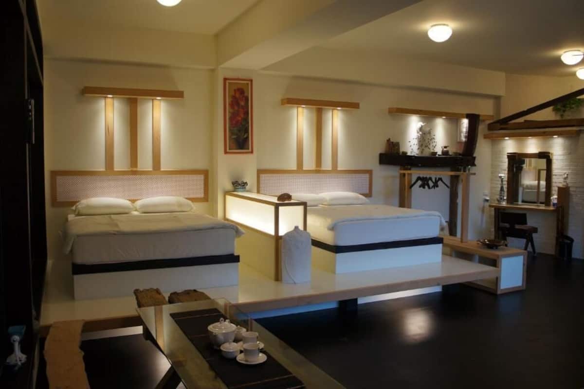 Une chambre d’hôtel moderne avec deux lits, un petit bureau et un service à thé sur une table d’appoint.