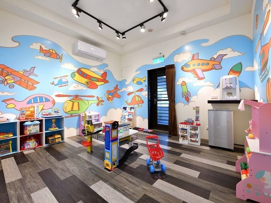 A children's playroom with colorful airplane murals, play shelves, and a toy car.