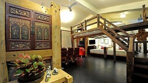 A room with a wooden staircase, a large decorative door, and a plant on a wooden table.