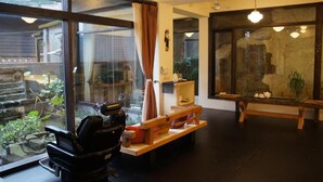 A room with large windows, a scooter, a wooden bench, and a small table with items on it.
