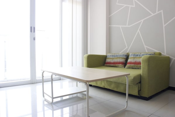 A modern room with a green sofa, a white table, and a geometric wall design.