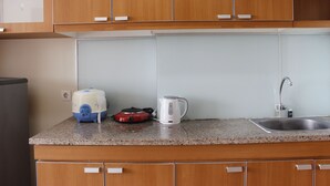 Una cocina con armarios de madera, encimera de granito, tetera, tostadora y pileta.