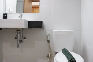 A bathroom with a white sink, mirror, and toilet. - Cozy Studio Apartment at Beverly Dago Residence (Bandung)