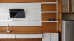 Una cocina moderna con armarios de madera, televisor integrado y refrigerador.