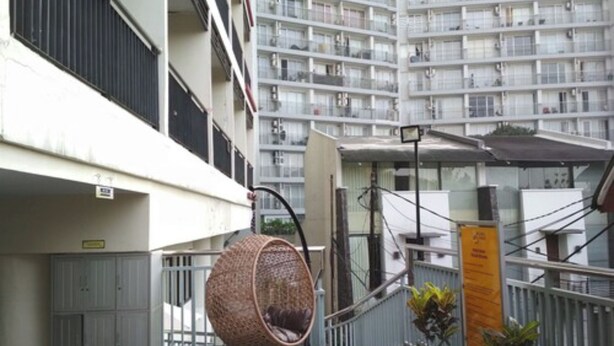 Un balcón con una hamaca colgante, plantas en macetas y vista a un edificio de gran altura.