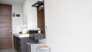 Una cocina compacta con un lavamanos integrado, un refrigerador pequeño y un taburete.