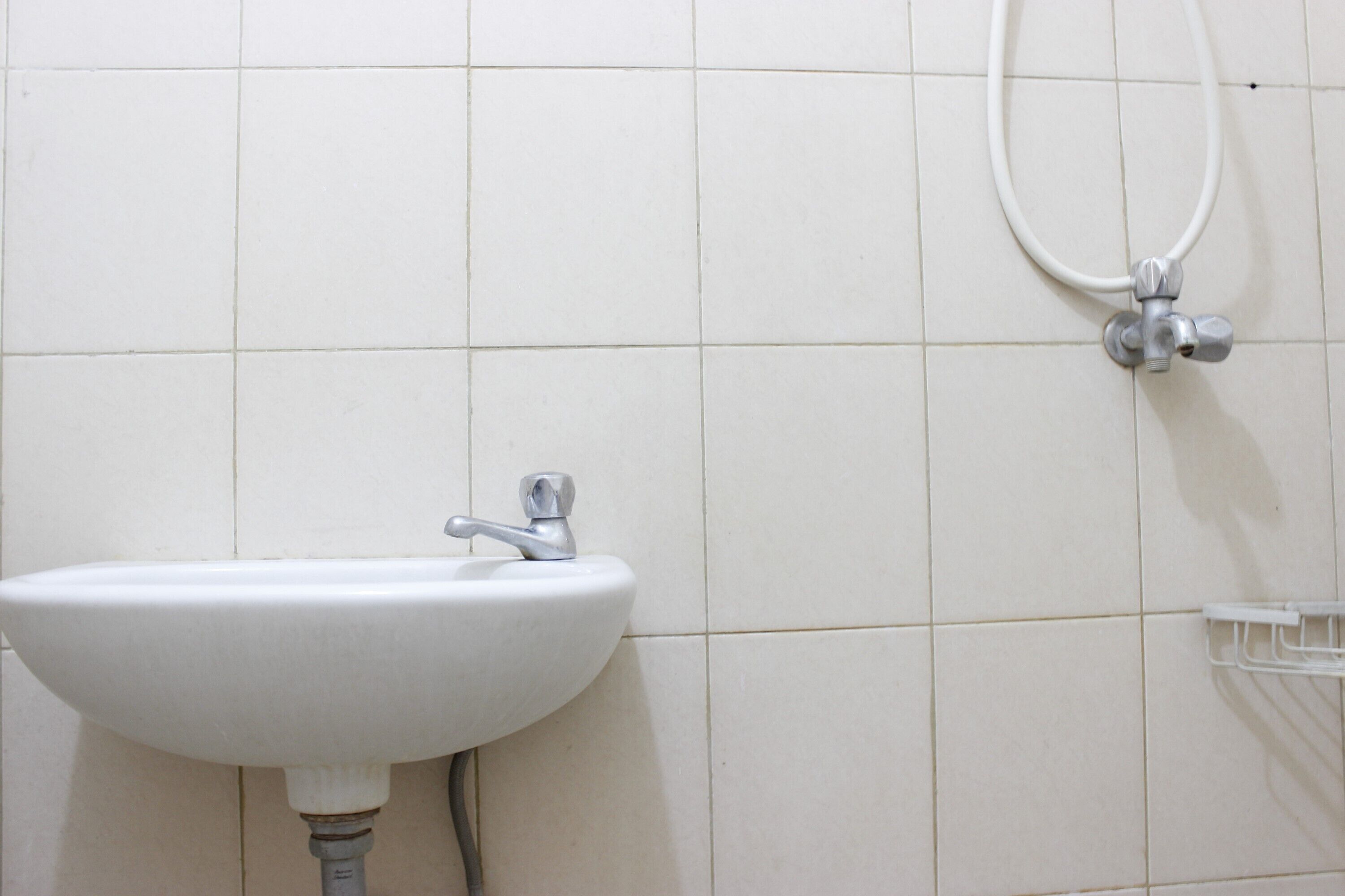 Un baño con un lavamanos blanco, ducha y toallero blanco.