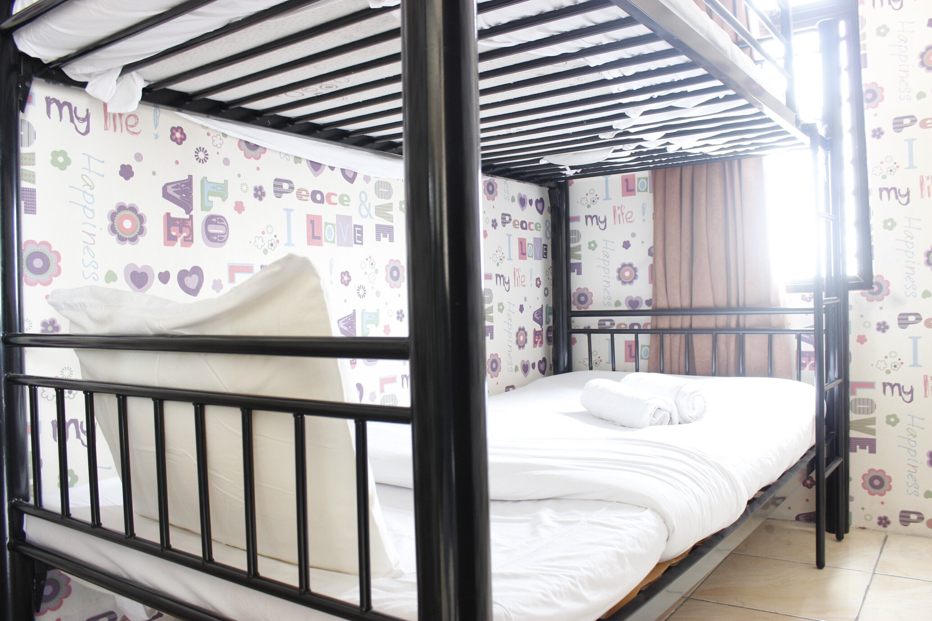 A bunk bed with a white mattress and pillows, a black metal frame, and a ceiling with a striped pattern.