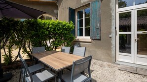 A patio with a table and chairs, a small tree, and a building with a window and door. - Holiday rental 5 personnes Château Belle Epoque Landes (Linxe)