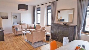A living room with a sofa set, a dining table with chairs, a fireplace, and a large mirror. - Apartmenthaus Lorbach (Solingen)